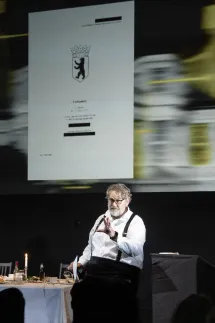 Andreas Beck liest aus einem geheimen Dokument, das hinter ihm auf eine Leinwand projiziert ist