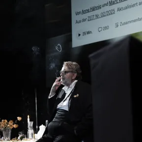 Andreas Beck sitzt an einer gedeckten Tafel und raucht eine Zigarette