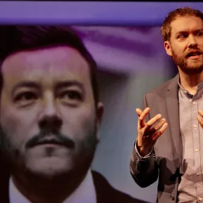 Calle Fuhr erklärt etwas, hinter ihm sieht man das Gesicht von René Benko