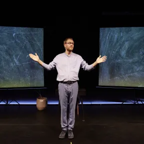 Calle Fuhr steht auf der Bühne vor zwei Schultafeln