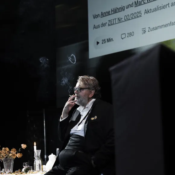 Andreas Beck sitzt an einer gedeckten Tafel und raucht eine Zigarette