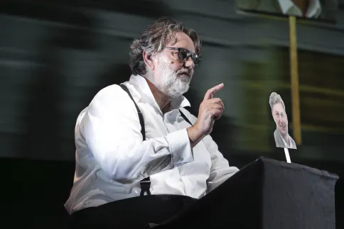 Andreas Beck hält ein Foto von Maximilian Krah in der Hand und steht an einem Pult