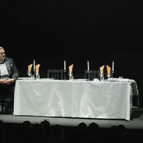 Andreas Beck sitzt an einer langen gedeckten Tafel