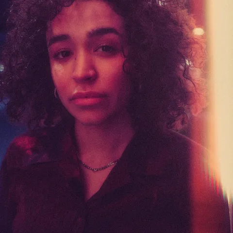 Paula blickt in die Kamera, sie hat rotes Licht im Gesicht
